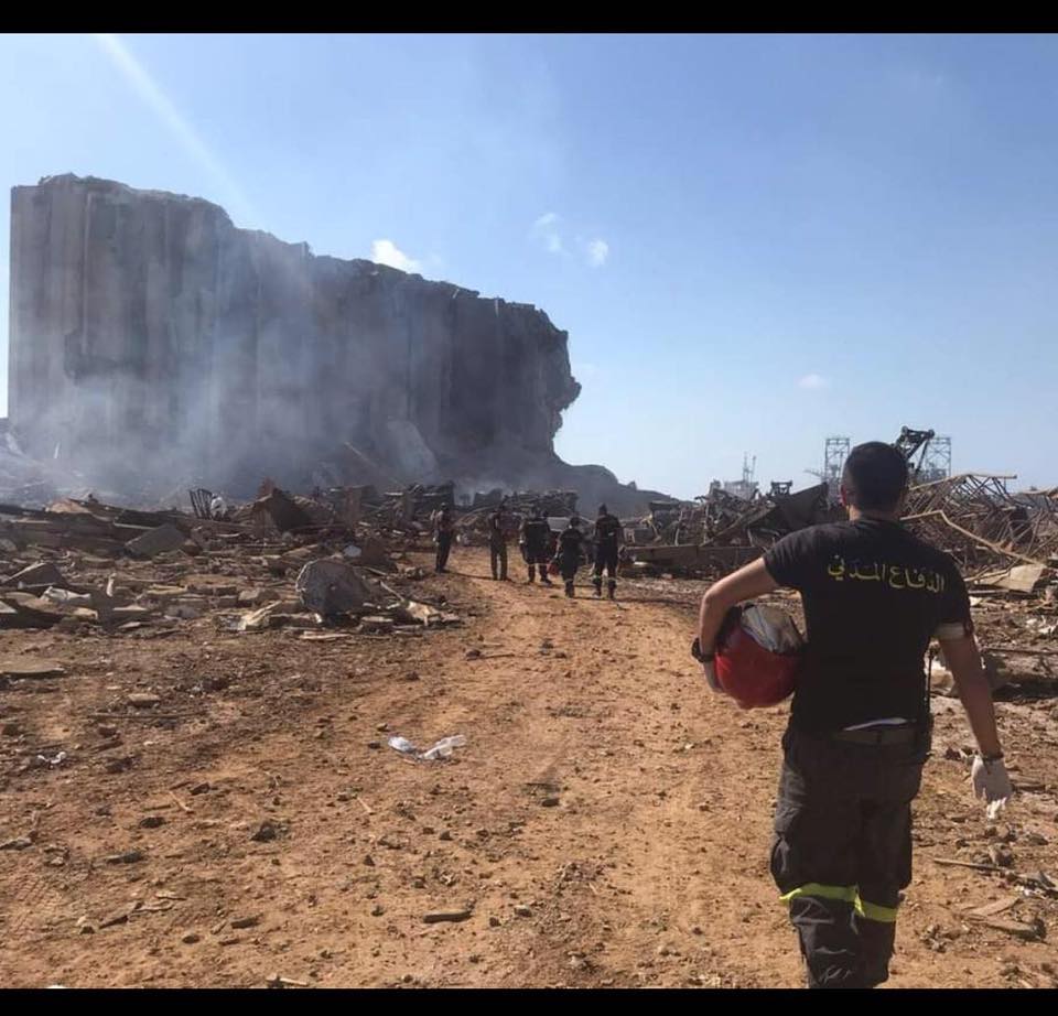 Um bombeiro, caminha em direção ao prédio ao local da explosão, de onde sai fumaça