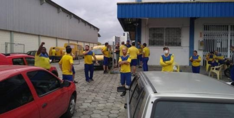 Na foto, estão cerca de 10 trabalhadores dos correios, no pátio de uma unidade da empresa