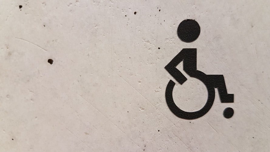 Fotografia. símbolo gráfico, representando uma pessoa em uma cadeira de rodas, sobre uma parede branca