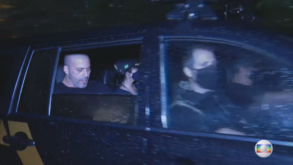 Deputado sendo levado preso no banco traseiro de um carro da policia.