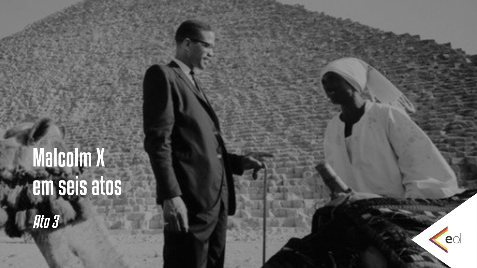 Malcolm em seis atos - Ato 3. Foto mostra ele conversando com uma mulher negra, tendo ao fundo uma pirâmide
