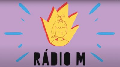 Rádio M. Reprodução da logomarca. Sobre um fundo roxo, o desenho de uma chama estilizada, em amarelo, com sombra veremelha, e dentro uma ilustração de uma menina, com uma antena na cabeça. Abaixo, em letras pretas, rádio m