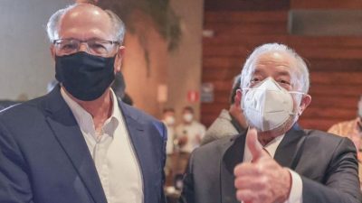 Alckmin e Lula em jantar. Os dois estão lado a lado, de terno e máscaras. Lula faz sinal de ok.
