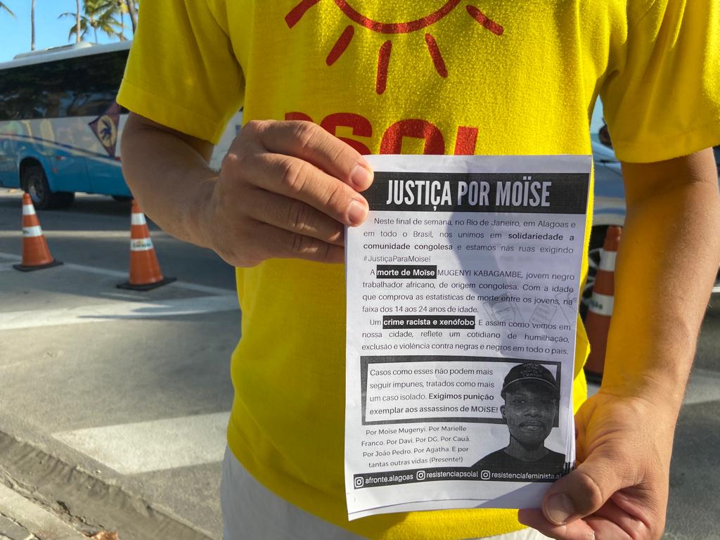 Militante do PSOL - com a camisa amarela e logomarca do partido - exibe um panfleto distribuído no ato.