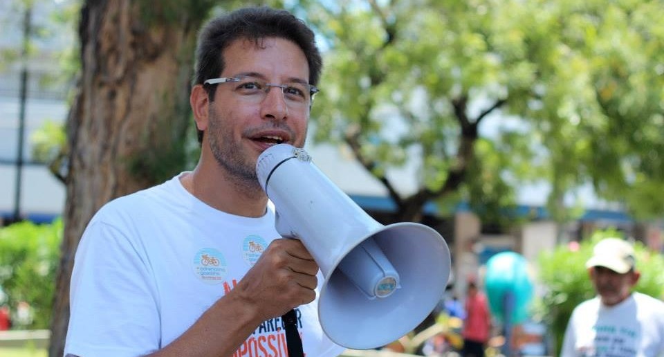 Renato Roseno. Foto de arquivo. Ele fala segurando um megafone. Usa óculos e camiseta branca.