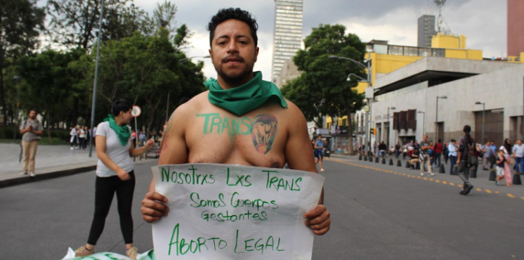 manifestante com uma placa escrito “Nós xs trans somos corpos gestantes. Aborto legal”.