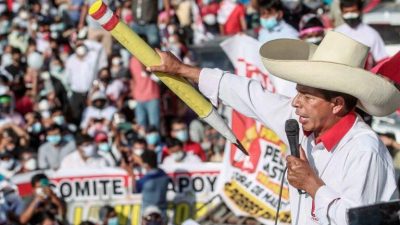 Castillo discursa em um comício de campanha. Ele usa chapéu, claro, segura o microfone e um lápis de madeira, grande, símbolo de sua profissão.
