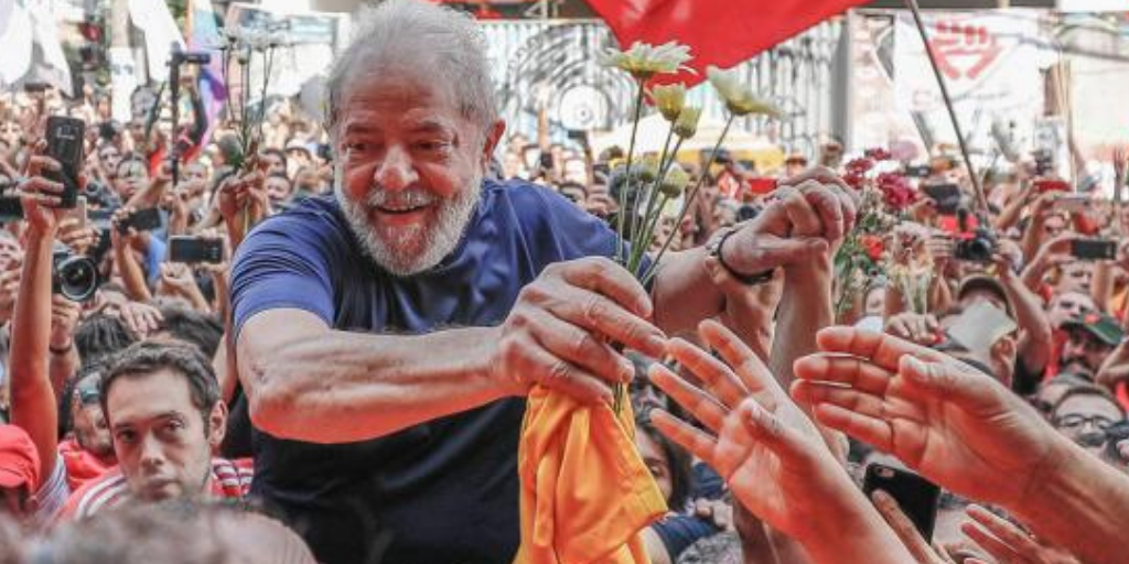 Lula aperta mãos de pessoas, carregado nos ombros