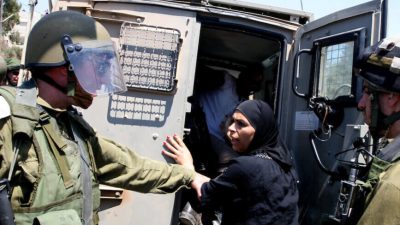 Palestina é presa por soldados, que a colocam em um veículo militar.