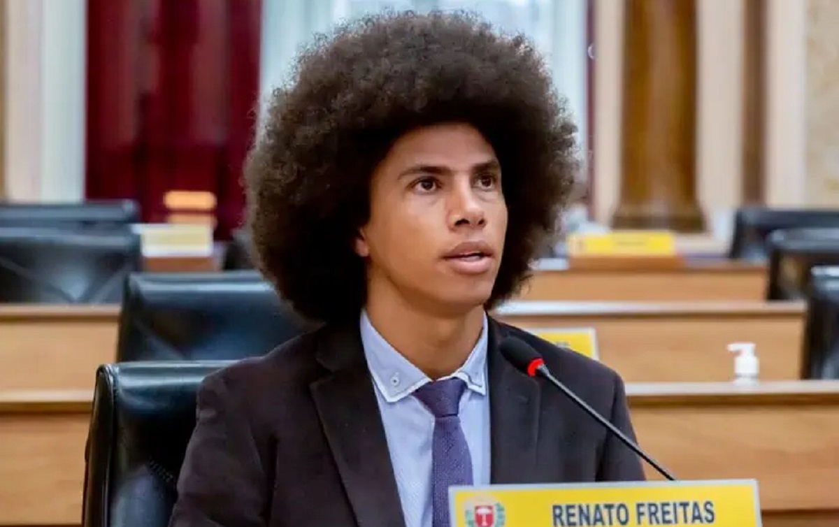 Renato Freitas, em Plenário. Ele usa terno azul marinho e camisa azul clara com gravata azul escuro. É um jovem negro e tem cabelos grandes. Está sentado.