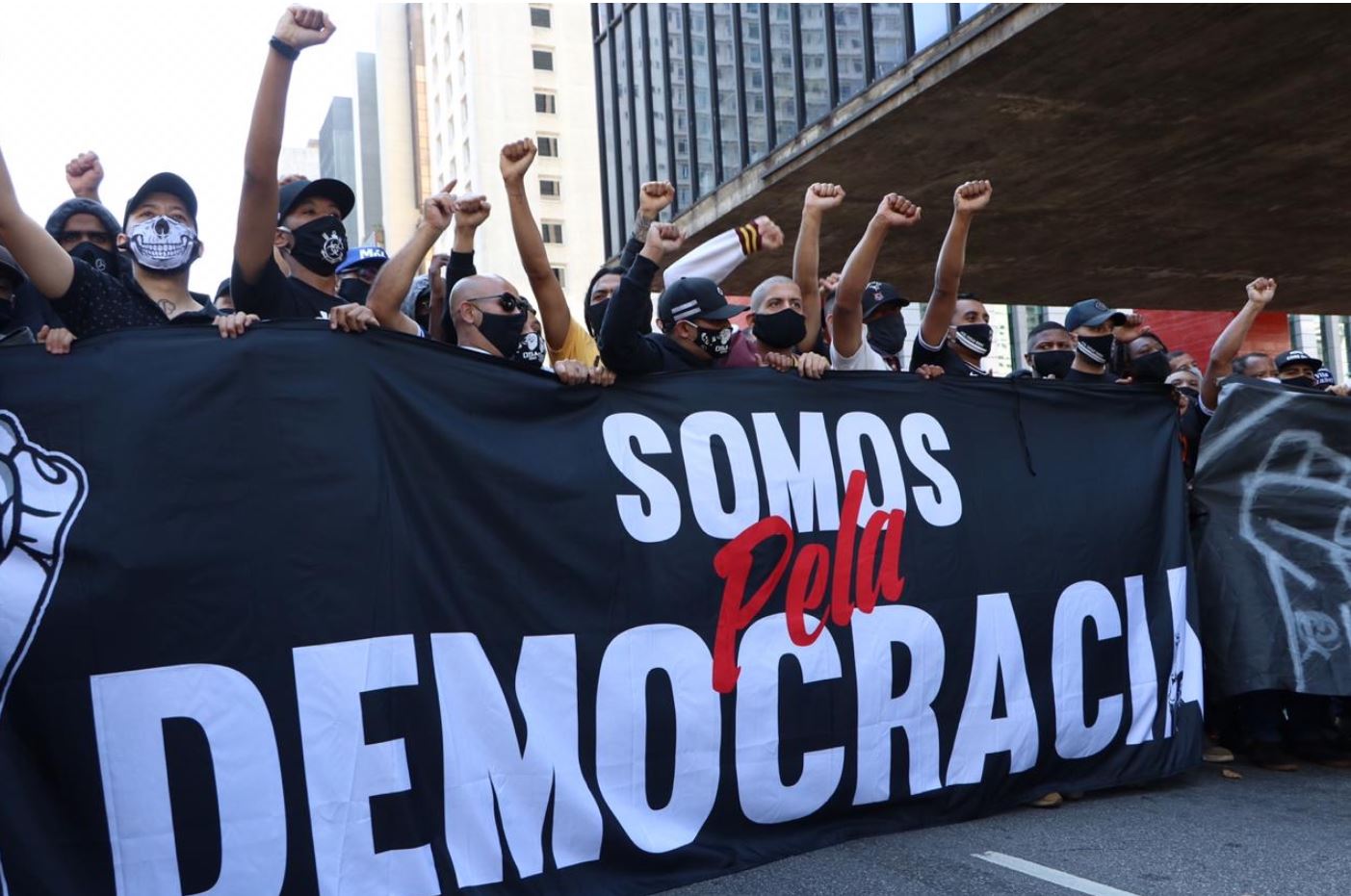 Faixa onde se lê "Somos pela democracia", com torcedores com punhos erguidos.