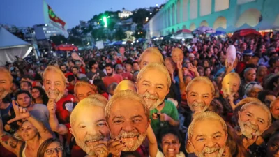 Em comício, pessoas posam com máscaras de Lula