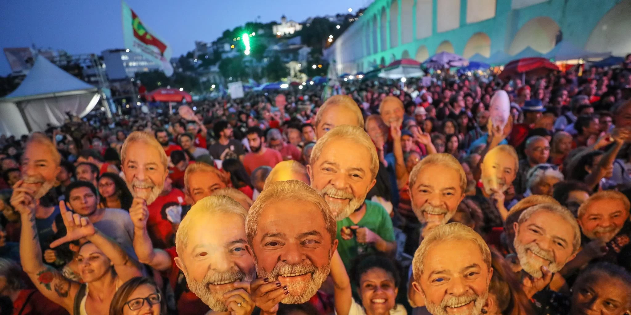 Em comício, pessoas posam com máscaras de Lula