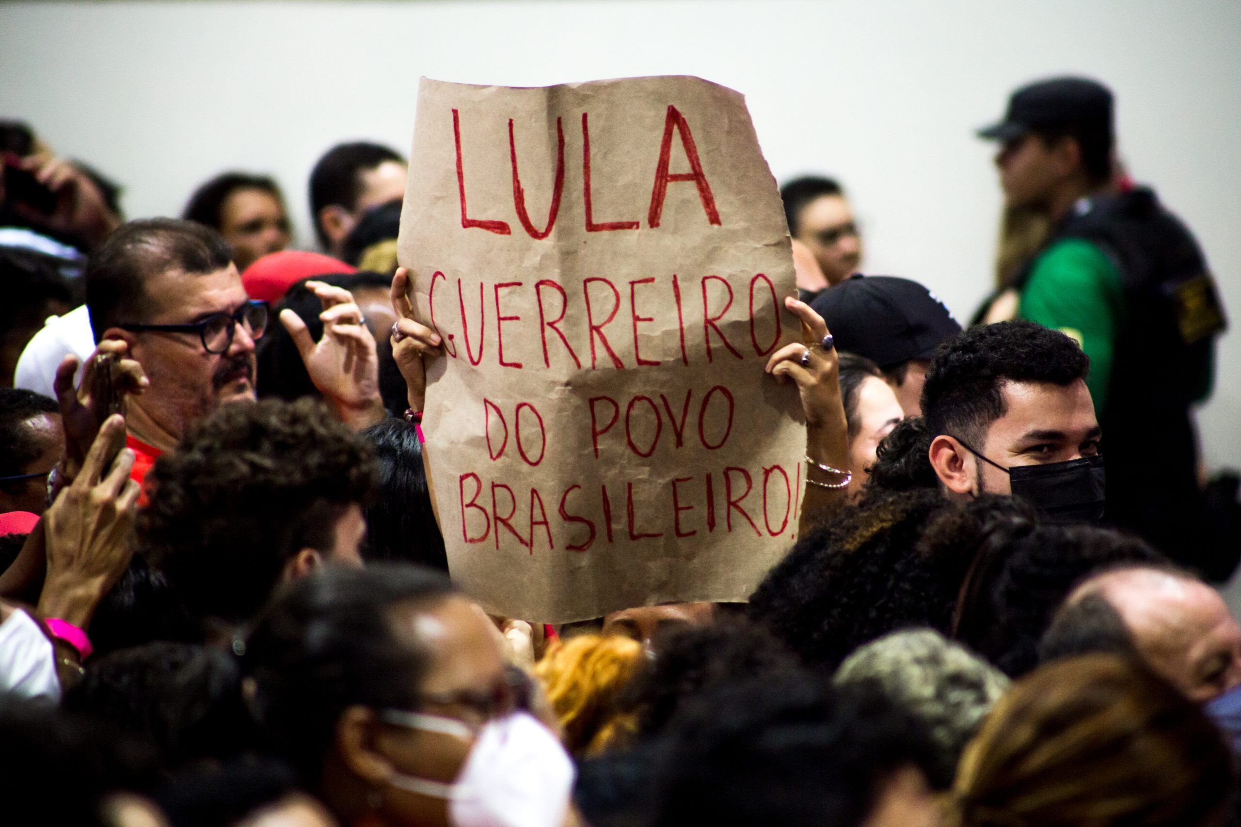 pessoa segura cartaz em comício com a frase: "Lula guerreiro do povo Brasileiro"